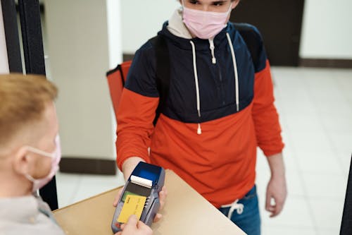 Free Man in a Face Mask Paying a Delivery Man Stock Photo