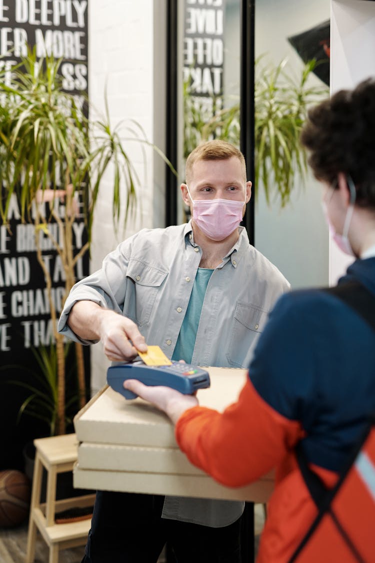 Man Wearing A Face Mask Paying For Pizza Delivery