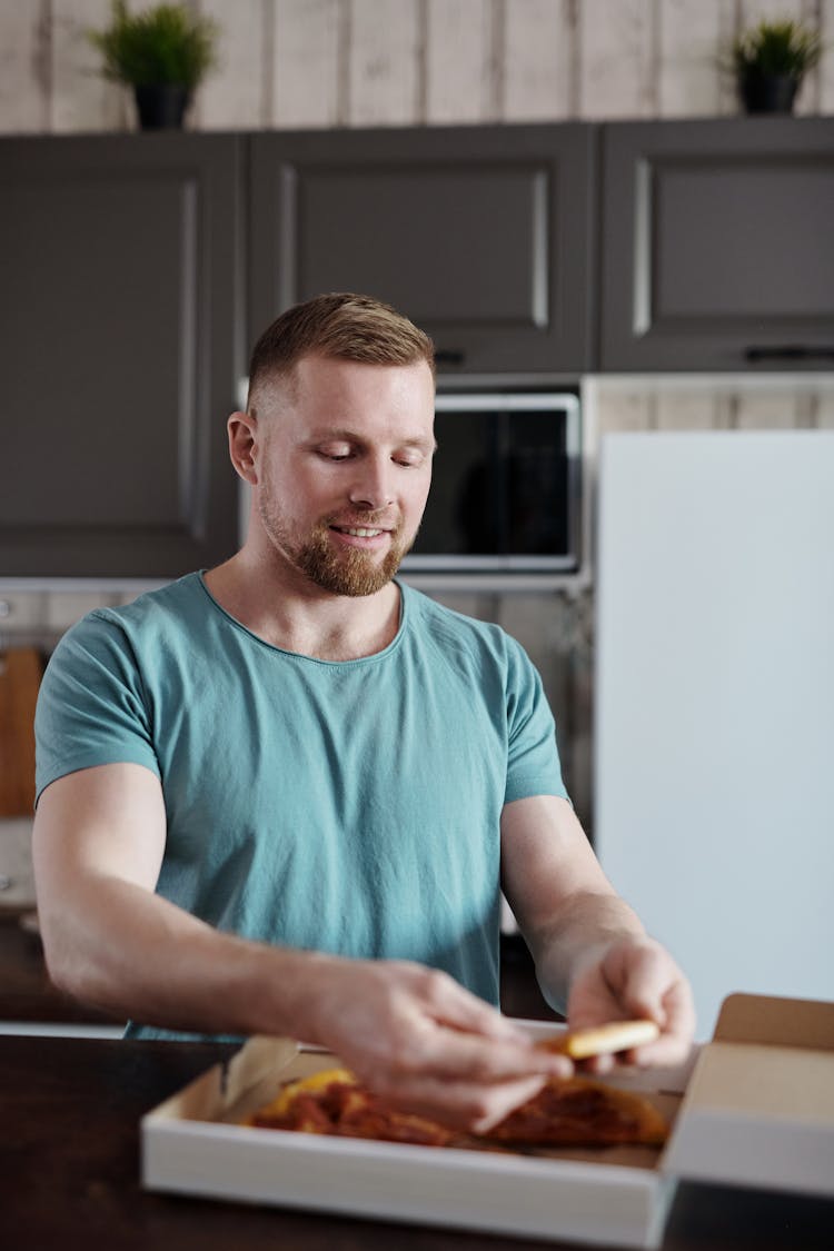 A Man Getting A Slice Of Pizza