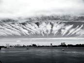 城市天际线呈黑白色，平静的海面上有独特的云纹