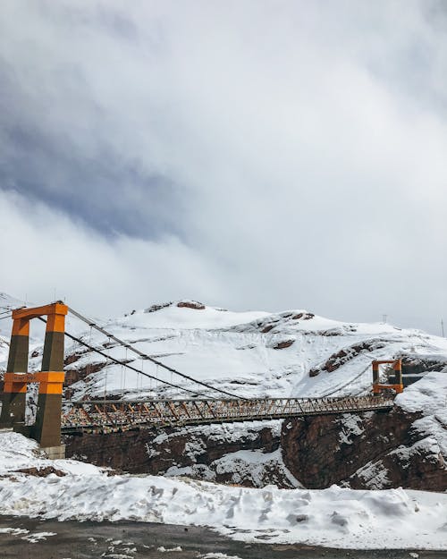 Suspension bridge over snowy mountain slope