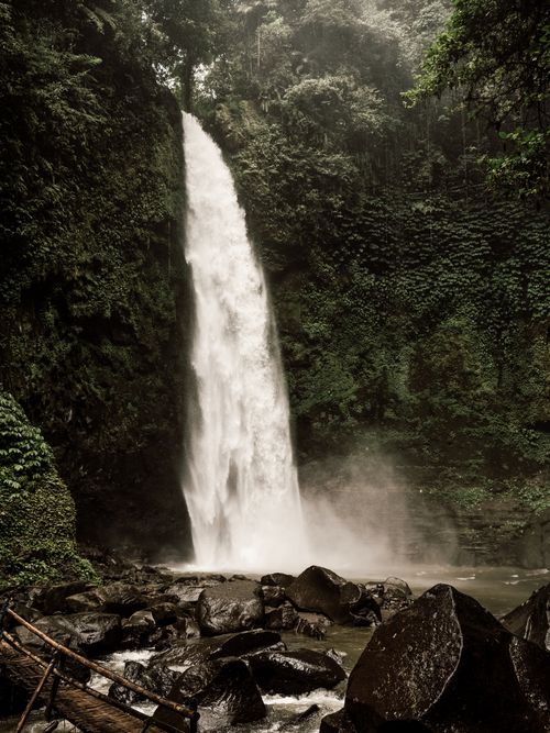 Free Experience the serene beauty of a Bali jungle with a cascading waterfall surrounded by lush vegetation. Stock Photo