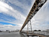 一座现代钢桥横跨河流，背景是生动的城市天际线