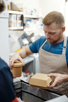 A man packing takeaway food in a restaurant, focusing on packaging with efficiency.