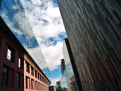 低角度镜头拍摄的现代摩天大楼，带有反光玻璃和多云天空