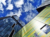 在清澈的蓝天下，色彩缤纷的摩天大楼立面带着玻璃窗，反射着云层