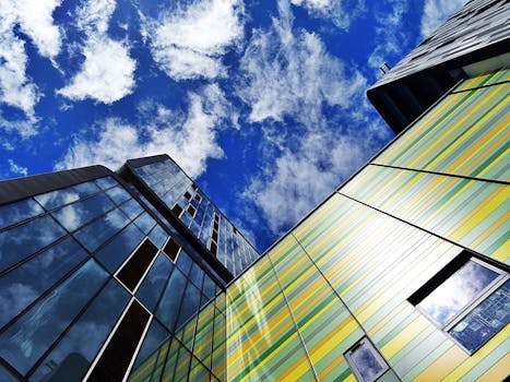 在清澈的蓝天下，色彩缤纷的摩天大楼立面带着玻璃窗，反射着云层