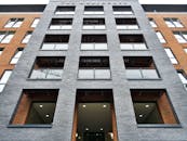 从低角度拍摄的现代砖砌建筑立面，展现了玻璃阳台与建筑设计