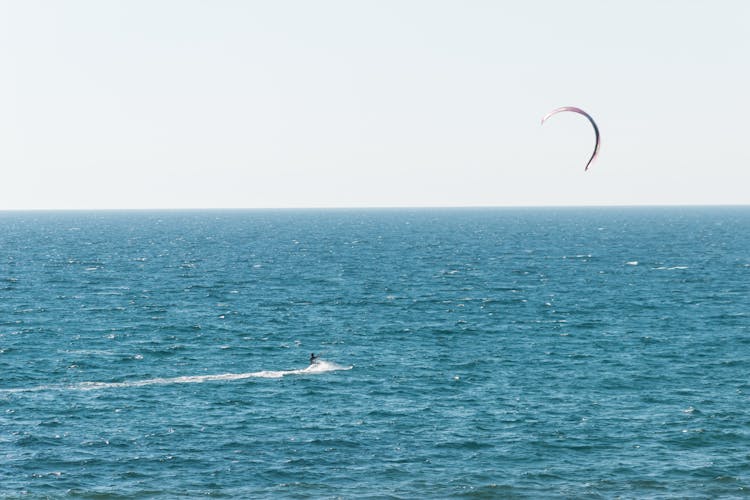 Unrecognizable Person Doing Parasailing While Swimming In Sea