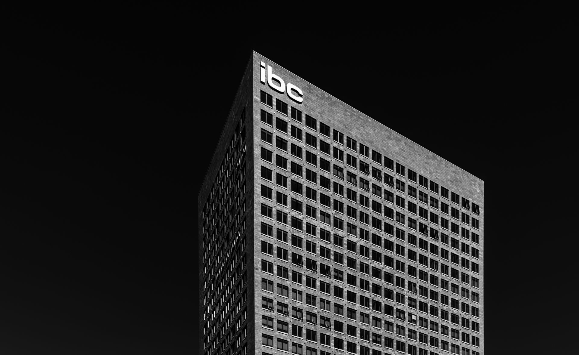 Black and white corner of contemporary multi storey office building on black background
