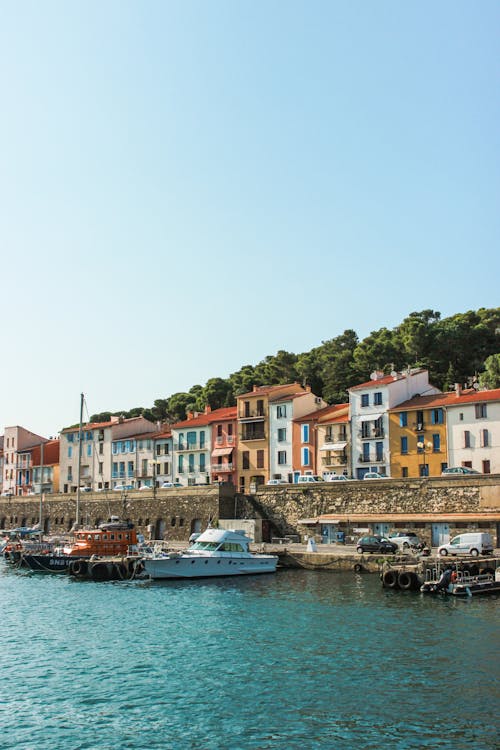 Cloudless light blue sky above ships in seaport near multi colored houses and greenery in tropical country