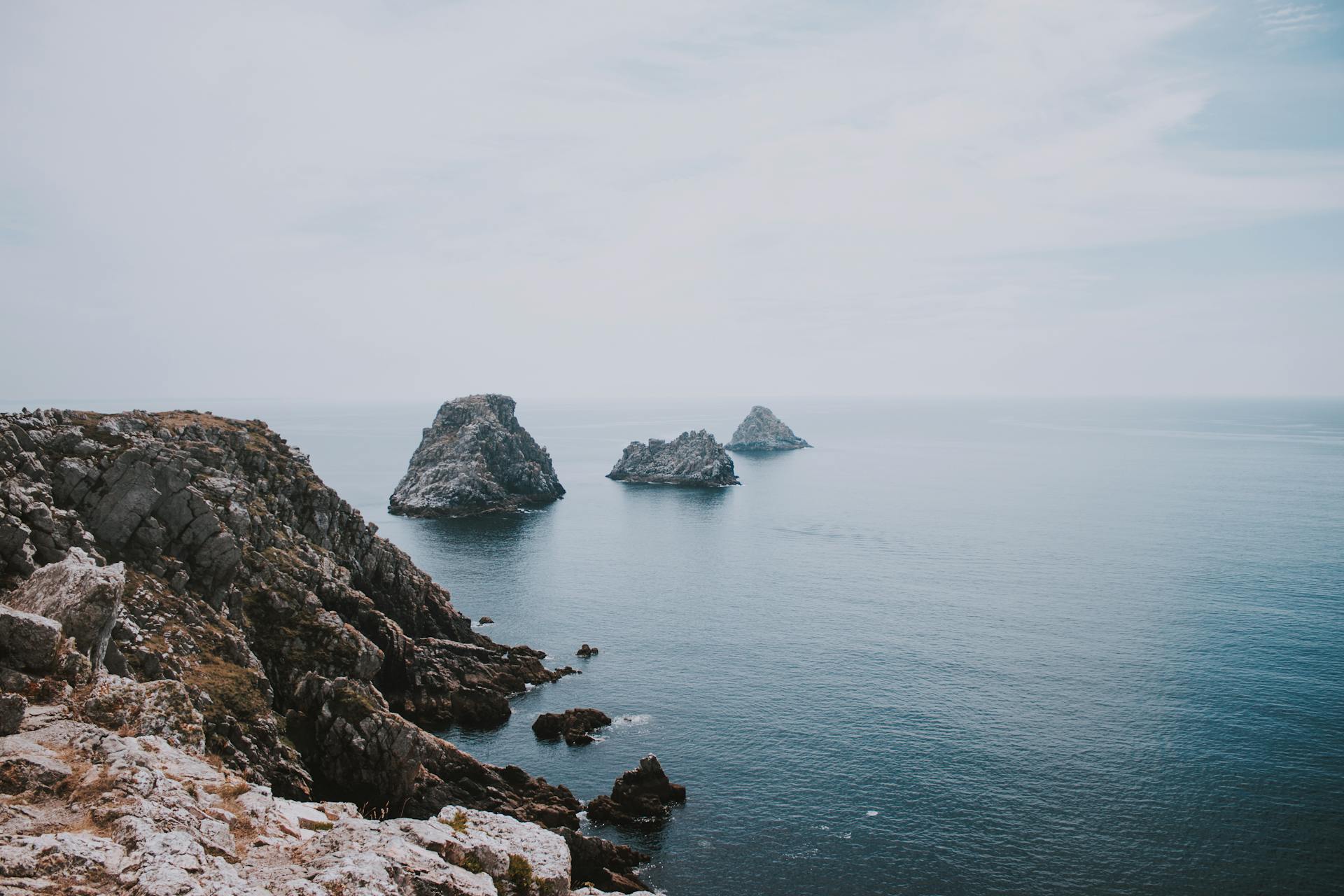 Picturesque view of sky above islands and rocky shore of vibrant blue endless ocean in daylight