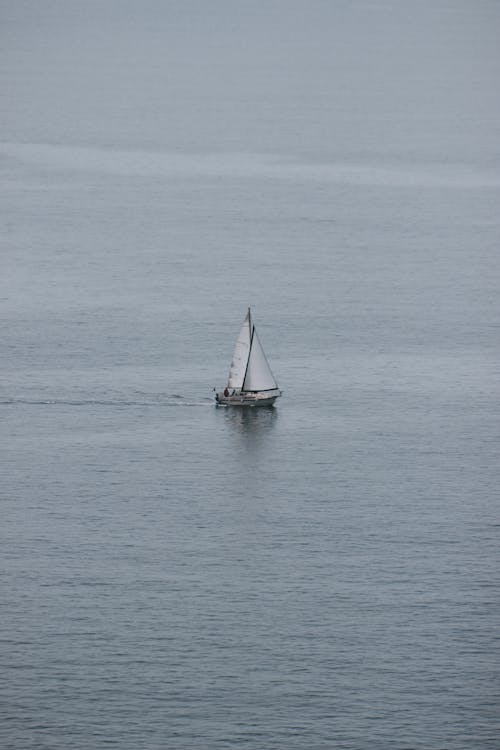 Modern white sailboat floating on rippling water of sea on peaceful cloudy day