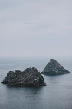 阴天平静的海水中，坐落着风景优美的海景与粗糙的岩石