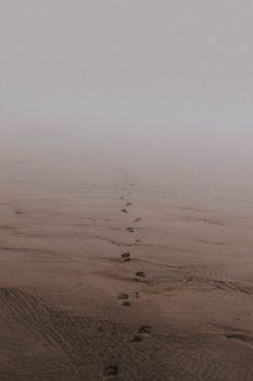 海边雾天湿沙上人类脚印的阴郁景色