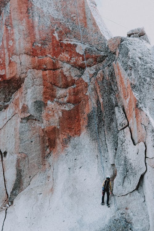 Strong alpinist climbing cliff on cloudy day