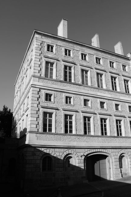 Low angle of black and white building with stone facade located on street in city and lit by sunlight