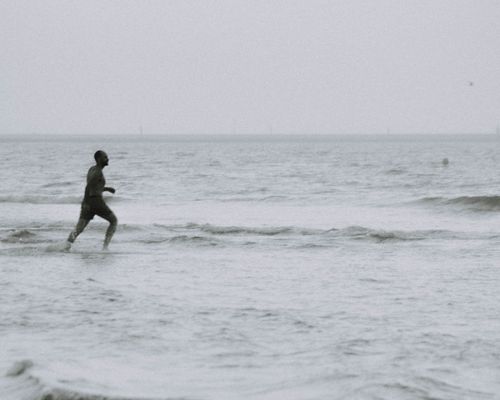 Free Side view of black and white male running in waving sea and enjoying summer vacation Stock Photo