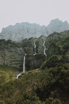 在阴沉的天气里，落基山的惊人景观位于灰色天空下的绿色地形附近