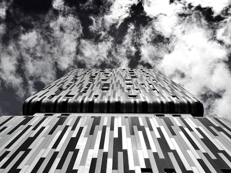 光滑、现代的建筑立面以单色调呈现，映衬着布满云朵的天空