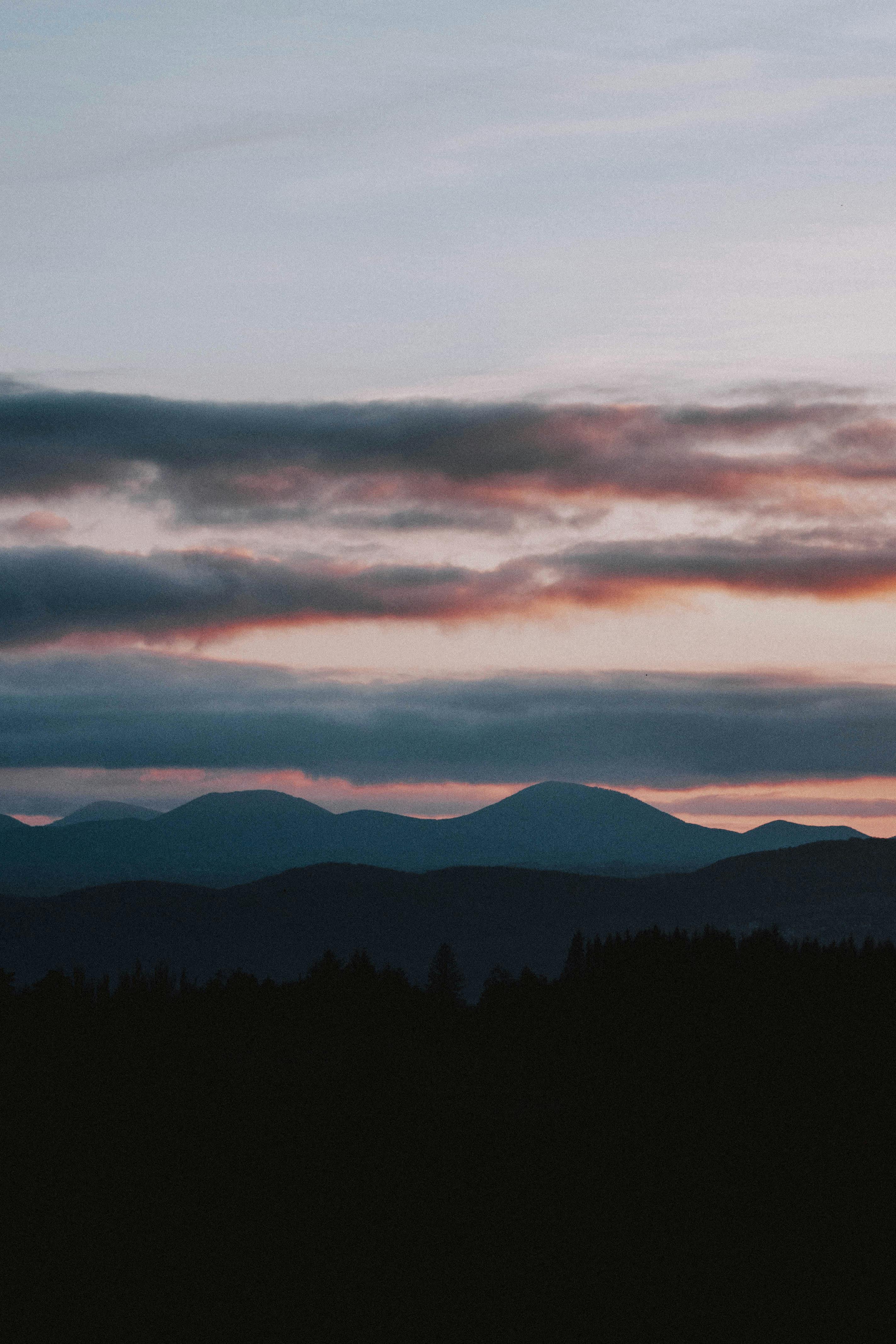 Slope with houses against mountains in clouds · Free Stock Photo