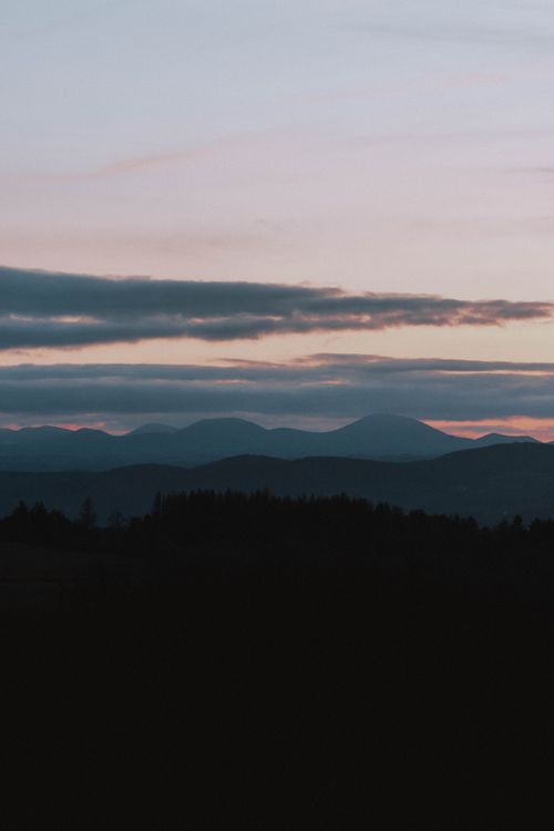 Free Breathtaking view of dark blue silhouettes of tall mountains covered with dense forest under colorful sky at sundown Stock Photo