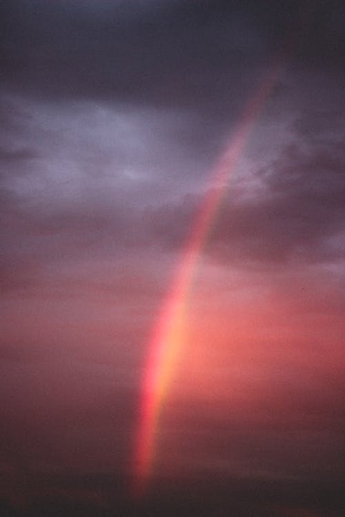 Free Picturesque view of dark cloudy sky with bright colorful rainbow at sunset in evening Stock Photo