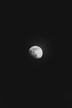 From below of black and white moon in waxing gibbous lunar phase shining in dark night sky