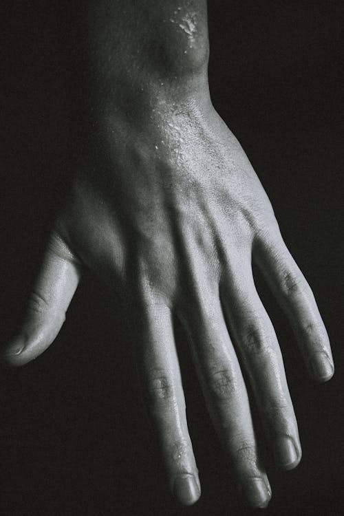 Wet hand of crop person against black background