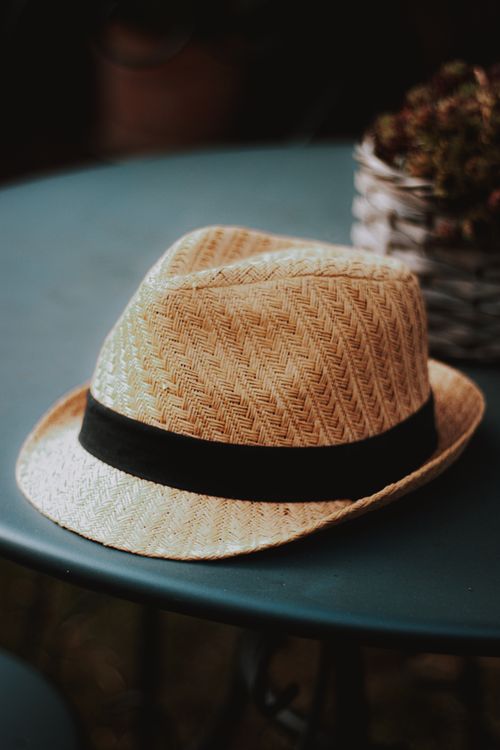 Free High angle of straw hat with wicker texture and black ribbon placed on table in cozy cafe Stock Photo