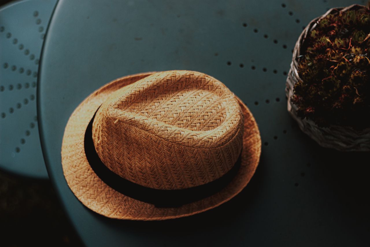 from above of round table in cafe with trendy natural straw hat with b