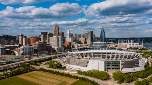 Exterior of modern Soldier Field in America surrounded by green trees and high multi storey office building next to junction and lawn