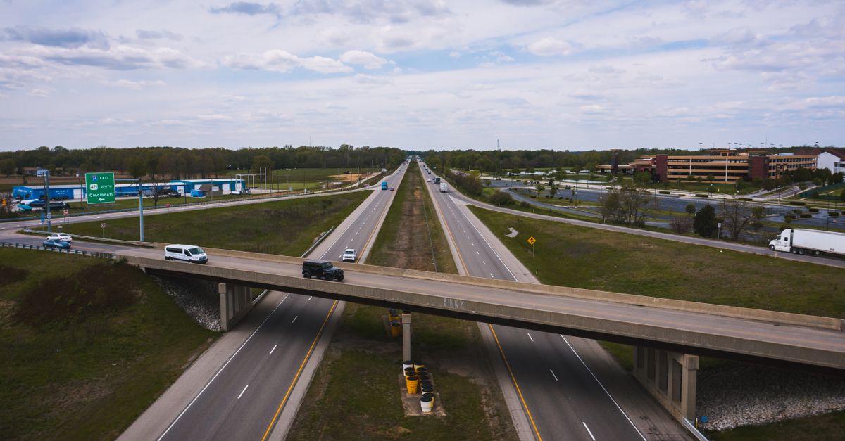 Aerial view of modern vehicles driving through asphalt roadway on cloudy day in city