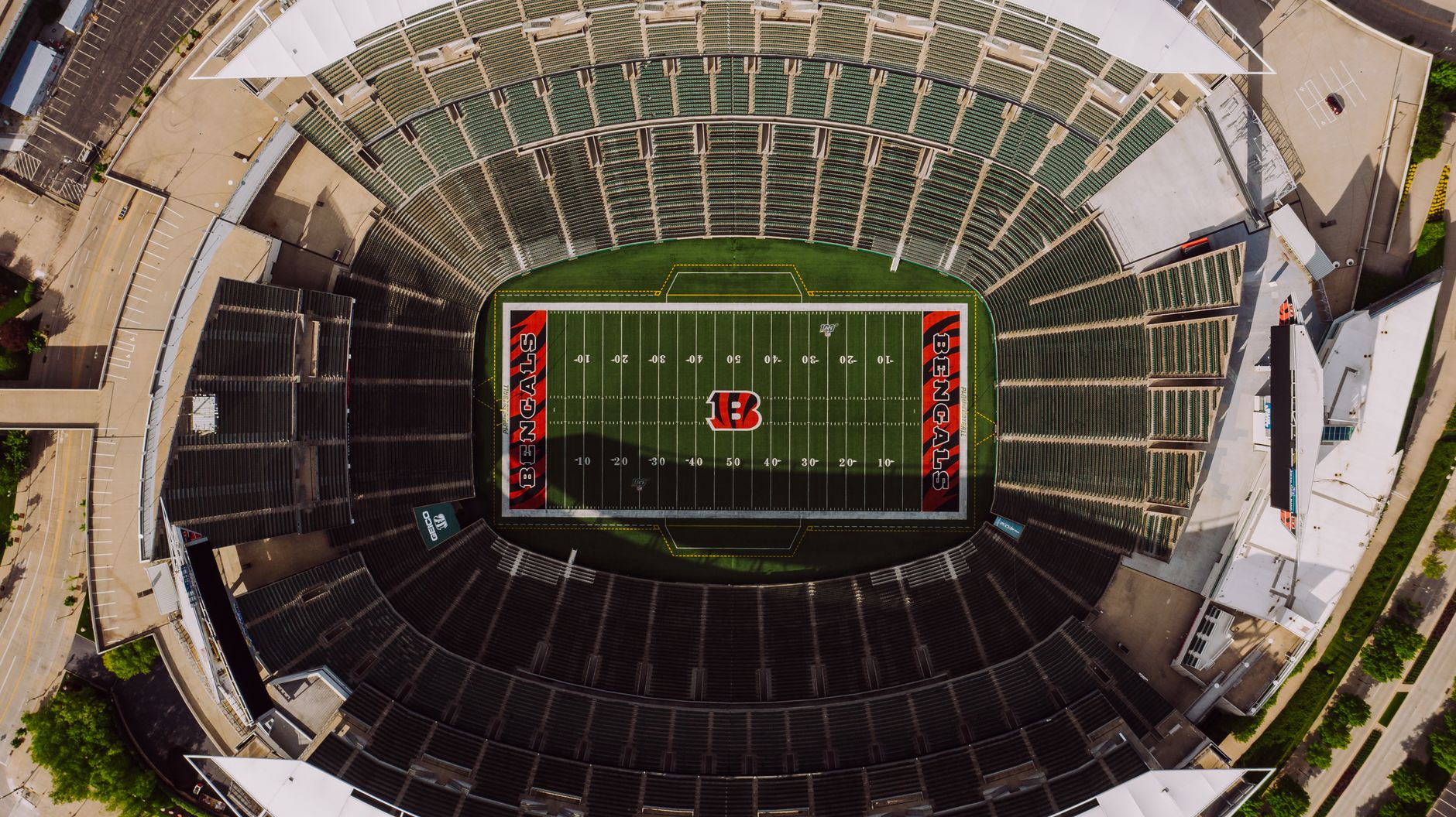 Top view of empty tribunes and American football stadium with white lines and emblem on sunny day