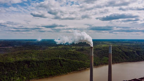 Smoke pipes near river and forest