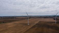 Wind generators in field under cloudy sky