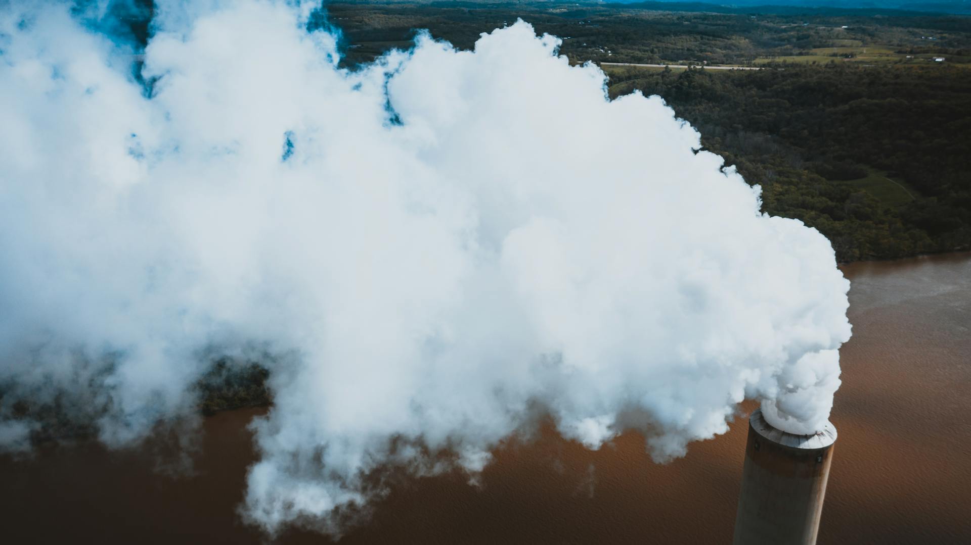 From above of thick fume stream coming out of masonry smokestack at power plant