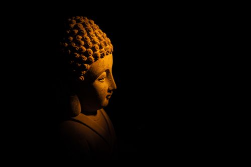 Free A Buddha statue partially illuminated in the dark, symbolizing peace and spirituality. Stock Photo