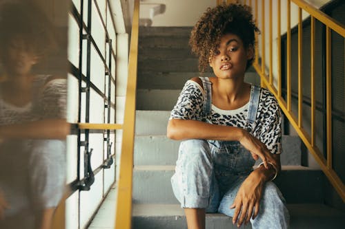 Stylish African American woman resting on stairs in building