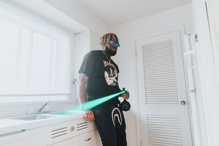 Bearded Man In Black T-shirt And Black Pants Holding A Laser With Green Light