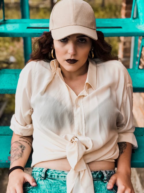 From above of crop attentive stylish ethnic hipster female with dark lips sitting on metal stairs and looking at camera