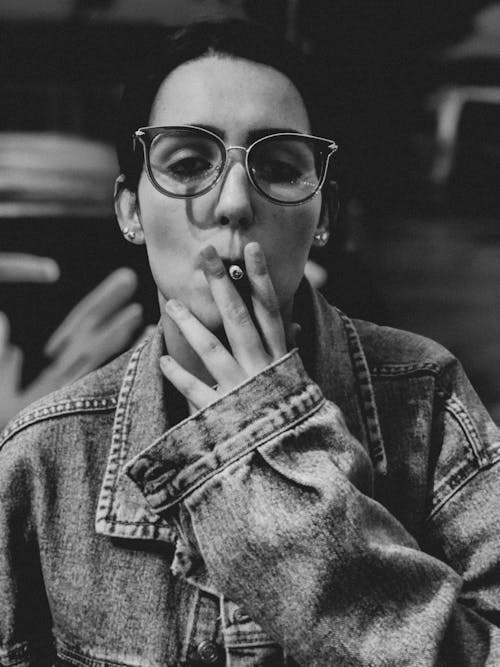 Free Monochrome Photo of a Woman in a Denim Jacket Smoking a Cigarette Stock Photo