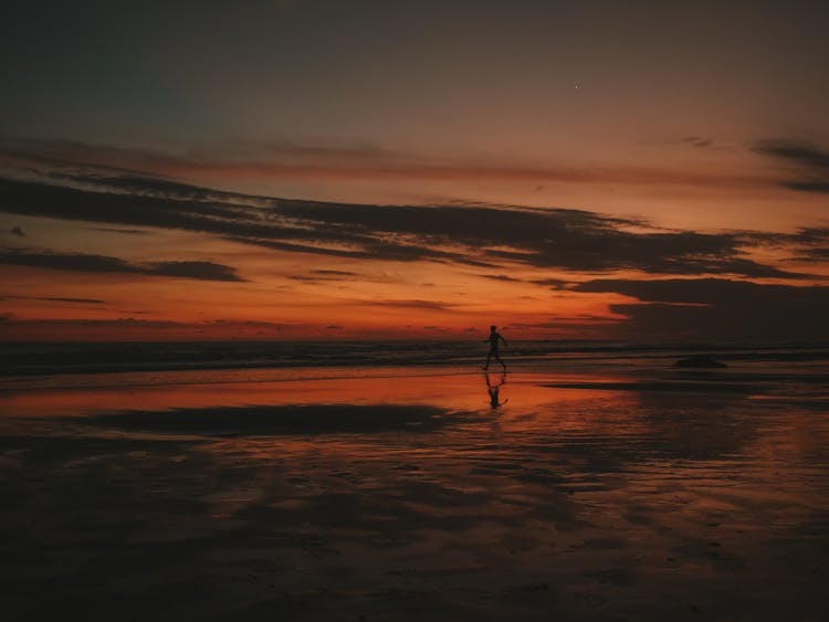 Silhouette Of Person Running On Beach During Sunset