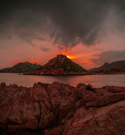 Free Picturesque view of rough mounts near ocean under sky with clouds at colorful sunset in twilight Stock Photo