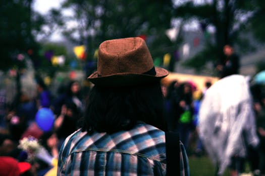 在充满活力的户外节日中，一个戴着帽子的人站在色彩缤纷的装饰旁