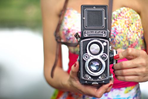 Free Close-up of a vintage Rolleiflex camera held by a woman in a colorful outfit. Stock Photo