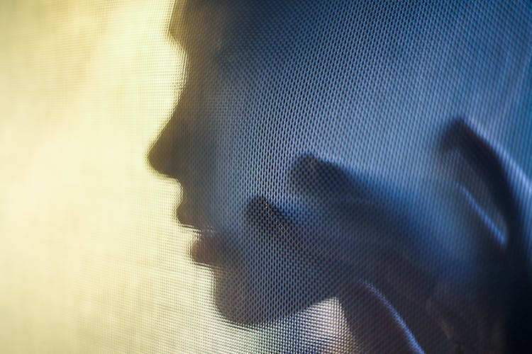 Silhouette Of A Woman's Face Behind A Fabric 