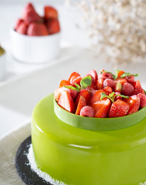 Free Vibrant green glazed cake adorned with fresh strawberries and mint leaves Stock Photo