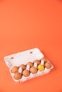 Set of raw chicken eggs in box on orange background