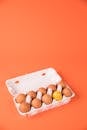 Set of raw chicken eggs in box on orange background